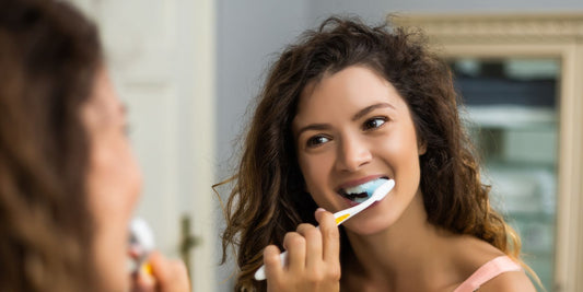Woman looking in the mirror while brushing her teeth.